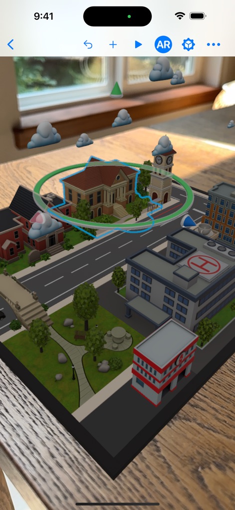 Reality Composer - Experience seamless integration of 3D scenes into the real world, as depicted by the virtual city overlaying a physical table and the clear outline of a selected object.