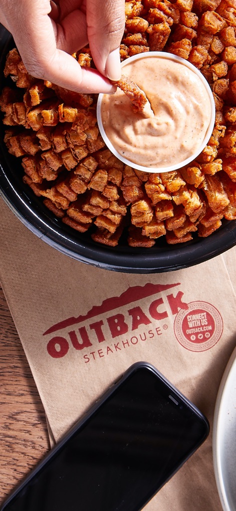 Outback Steakhouse - This image highlights the convenience of enjoying Outback favorites, featuring the iconic Blooming Onion and prominent Outback Steakhouse branding, suggesting easy order pickup or delivery.
