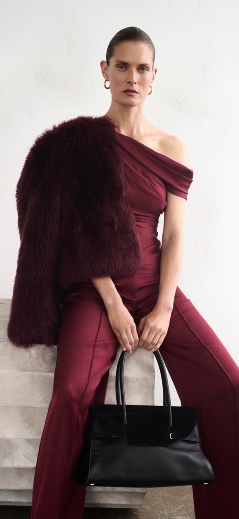 Bloomingdale's: Online Store - This captivating image displays a luxurious burgundy jumpsuit paired with a faux fur jacket, highlighting the app's aspirational fashion content and designer handbags.